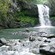 Um riacho rochoso coleta a água de uma cachoeira